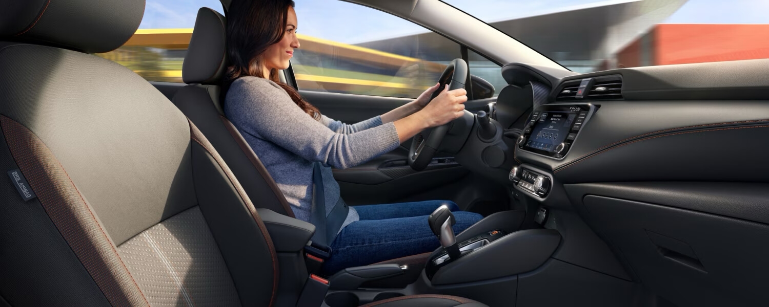 Femme au volant de la Nissan Versa 2024 incluant les technologies embarquées.