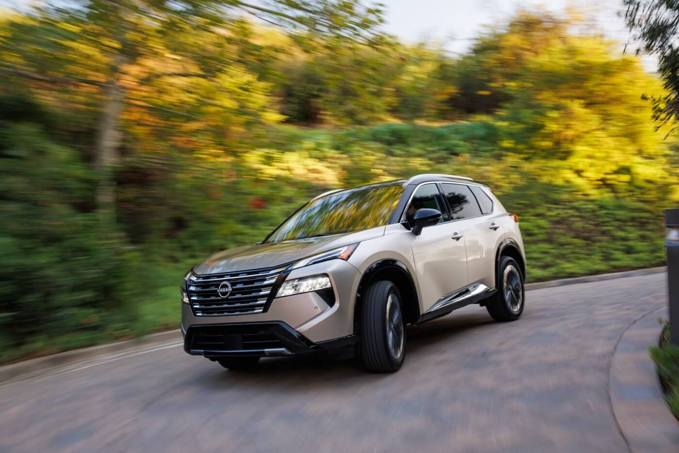 Vue 3/4 avant du Nissan Rogue 2025 roulant sur un chemin en pavé.